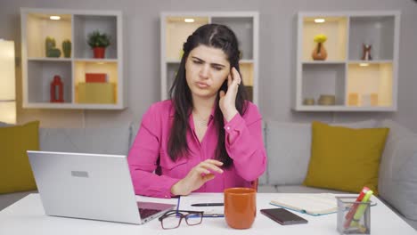 home office worker woman scratches her ears looking at camera.