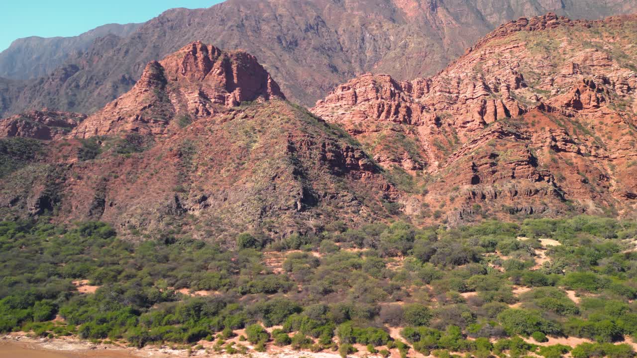Montagne di roccia rossa e alveo del fiume con vegetazione verde sotto il cielo blu