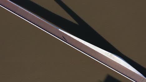 Aerial-shot-of-a-sleek-bridge,-Puente-de-la-Mujer,-casting-long-shadows-on-the-water,-a-minimalist-urban-scene