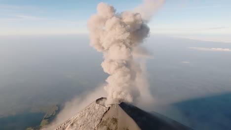 aerial: smoke coming out of fuego volcano crater during sunrise in guatemala