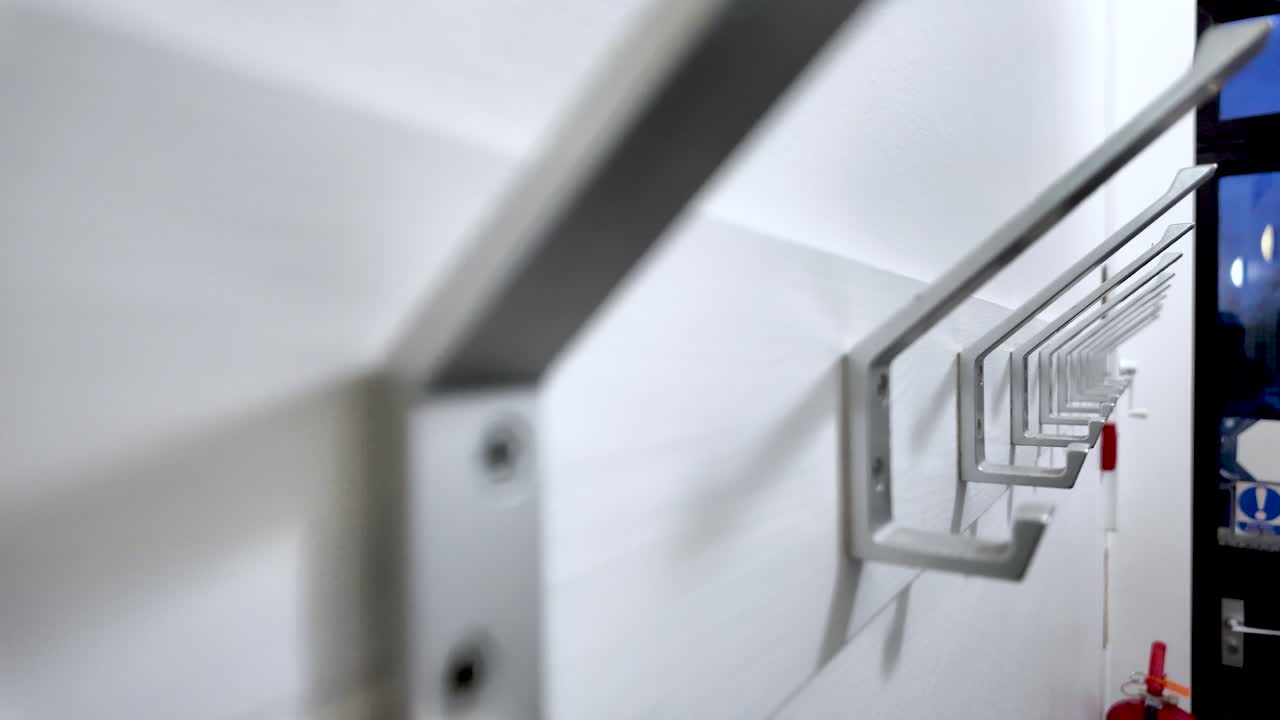 Ganchos de metal fixados em parede branca em elemento de design de interiores de corredor para pendurar roupas e acessórios em estilo minimalista de casa ou escritório moderno