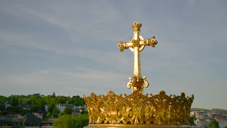 golden cross in front of the basilica of the immaculate conception of our lady of lourdes. upper basilica of the marian sanctuary of lourdes in france.