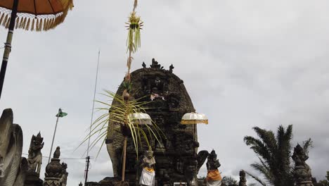 balinese temple in the streets of batuan, sukawati, dragon statues, guardians, umbrellas and offerings in the architectural entrance of the hindu bali religion sacred space