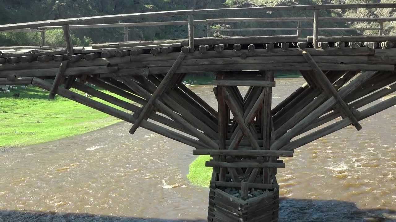 Alte Holzbrücke über einem fließenden Fluss in einer ländlichen Landschaft