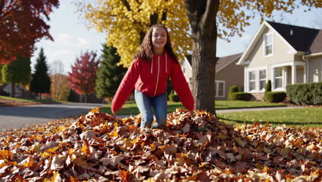 girl playing and jumping in a pile of autumn leaves