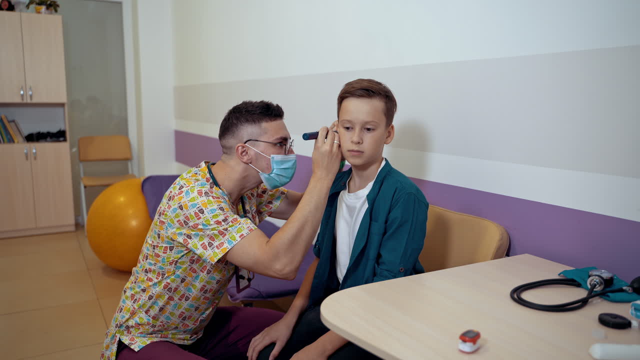 An otolaryngologist examines the ears of a little boy. Kid at pediatric clinic.