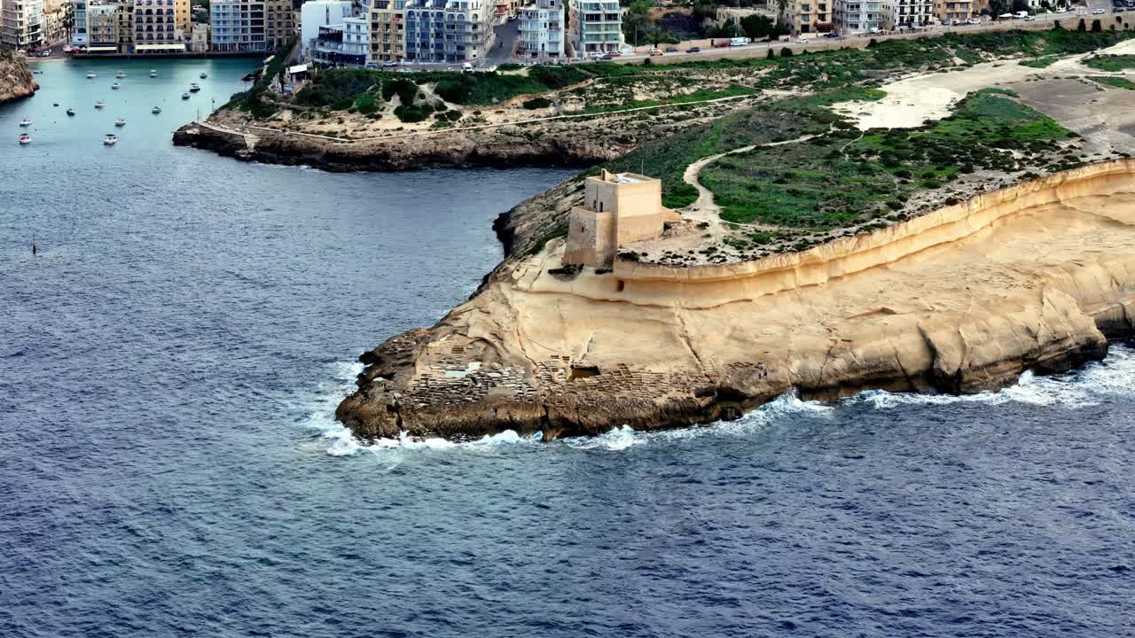 Storica Batteria Qolla l-Bajda con vista sulla Baia di Xwejni e sulle acque azzurre del Mediterraneo in una soleggiata mattina d'estate a Zebbug, Isola di Gozo, Malta, con vista dall'alto delle scogliere costiere calcaree