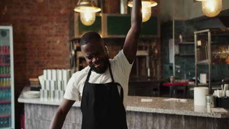 a waiter in a black apron in a doner market dances with wireless headphones. video filmed in high quality