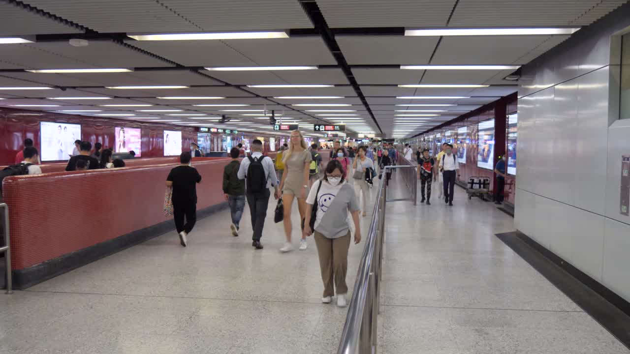 Commuters walking through a busy subway station hallway