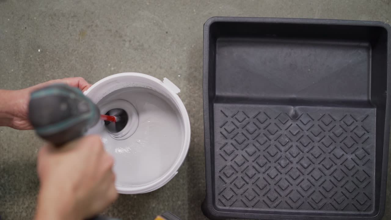 The white paint is mixed in a bucket with a drill. Drill paddle mixer on a bucket with white paint, DIY tools and accessory, banner