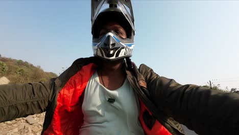 indischer radfahrer mit jacke, der motorrad auf indischem straßensporthelm mit handstunt fährt