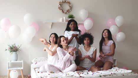 carefree young diverse women celebrate pajama party throw confetti up