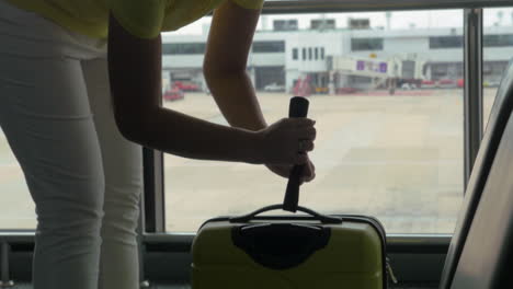 woman weighing luggage with hand scales