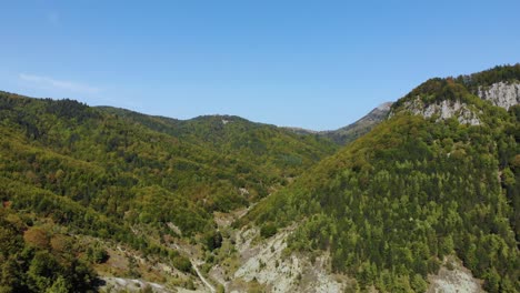 green forests on mountain's slopes through beautiful valley at autumn, aerial view