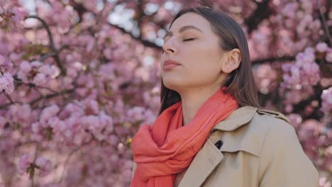 woman using nasal spray under cherry blossom trees