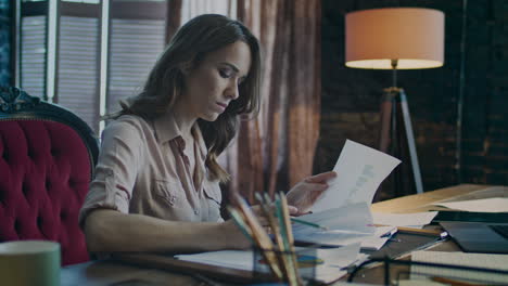 Focused-businesswoman-scanning-document-and-nervously-throwing-pencil-down