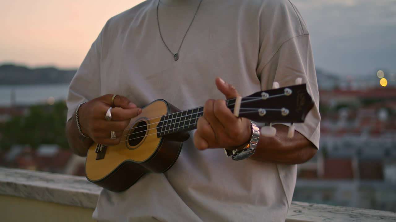 hombre pensativo firmando la terraza del atardecer el fin de semana. hombre tocando el ukulele por la noche