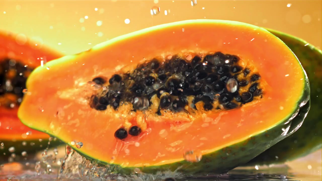 Schizzi d'acqua al rallentatore su papaya fresca tagliata a metà