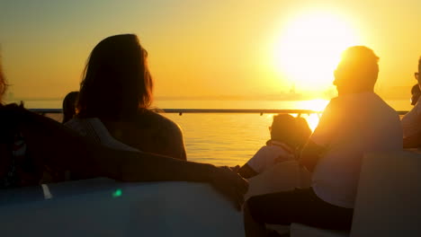 people on a boat enjoying a golden sunset over water