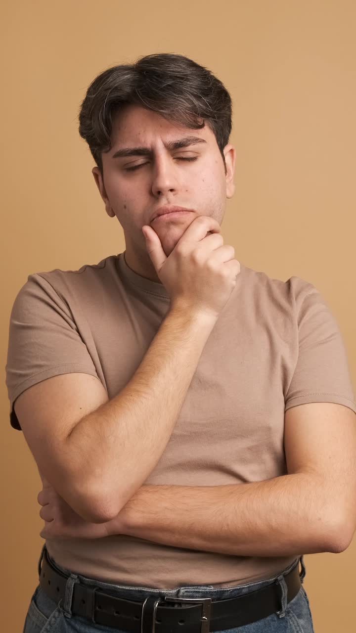 Doubtful man standing hand on chin with thoughtful expression
