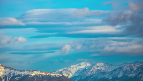 Abstrakte-Wolken,-Die-Sich-Am-Blauen-Himmel-über-Schneebedeckten-Bergen-Bewegen
