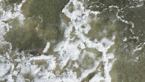 Top-down-view-of-semi-frozen-water-with-snow-patches-in-Southampton,-tranquil-nature-scene