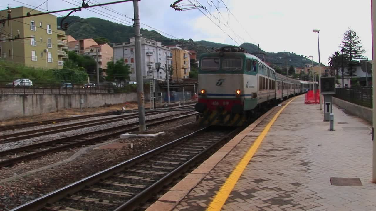un tren pasa por un patio de trenes y una ciudad en sicilia italia
