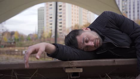 homeless man lying on bench and sad and dejected.