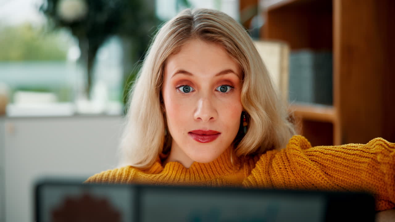 Kvinde kigger på bærbar computer med overrasket udtryk