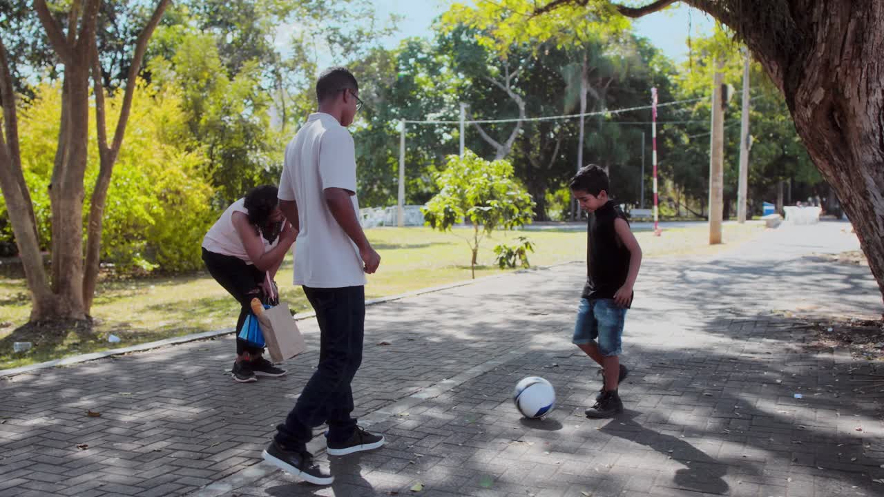 Family playing soccer in a park