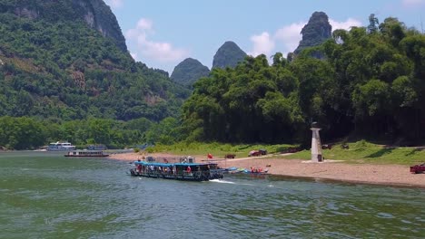 sightseeing boat full of tourists departing on a trip on the magnificent li river from guilin to yangshuo, china