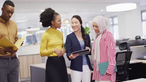 group of diverse business people using tablet and talking in office, slow motion