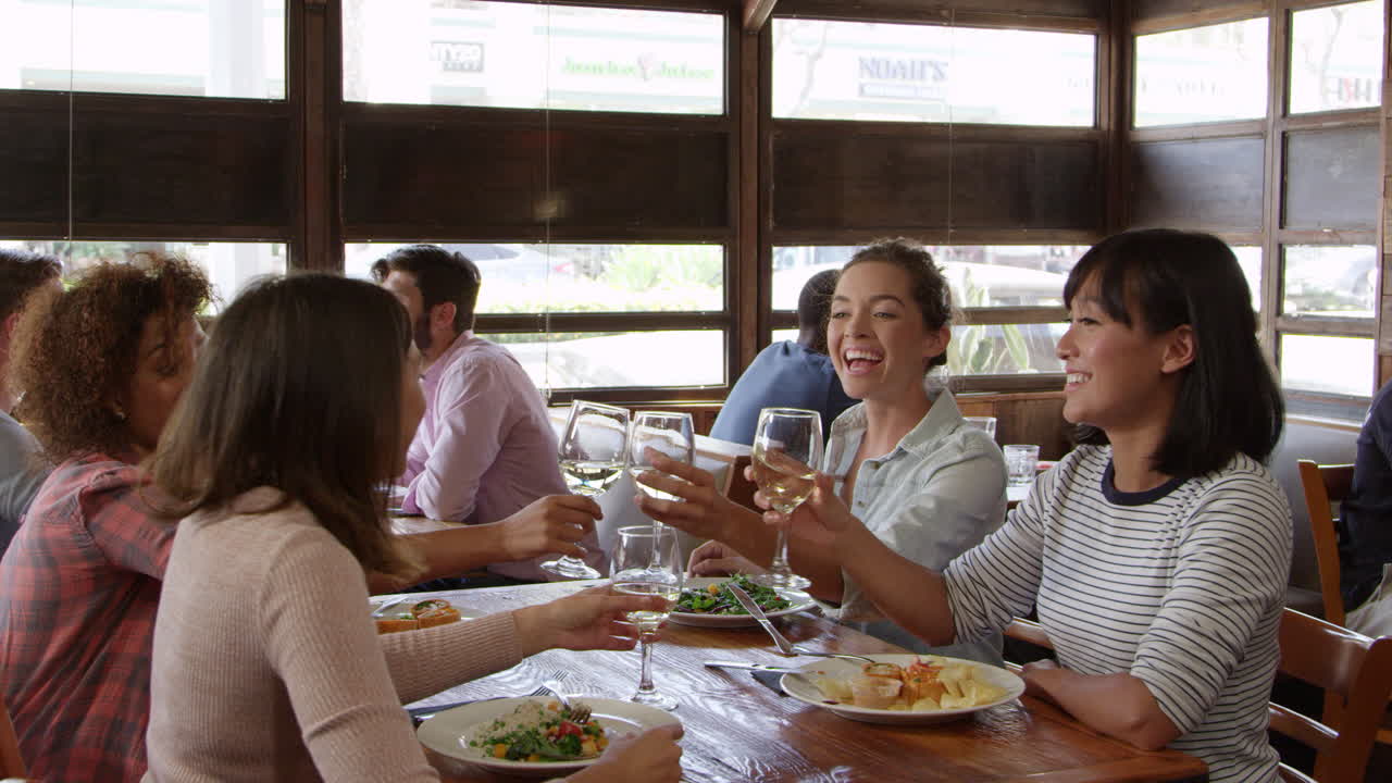 amigas haciendo un brindis durante el almuerzo en un restaurante, filmado en r3d