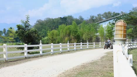 person riding an atv by a white fence