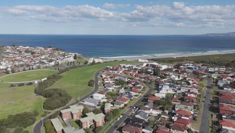 drone dolly above suburban homes and apartment condos along side of grassy green space overlooking ocean in port kembla nsw australia