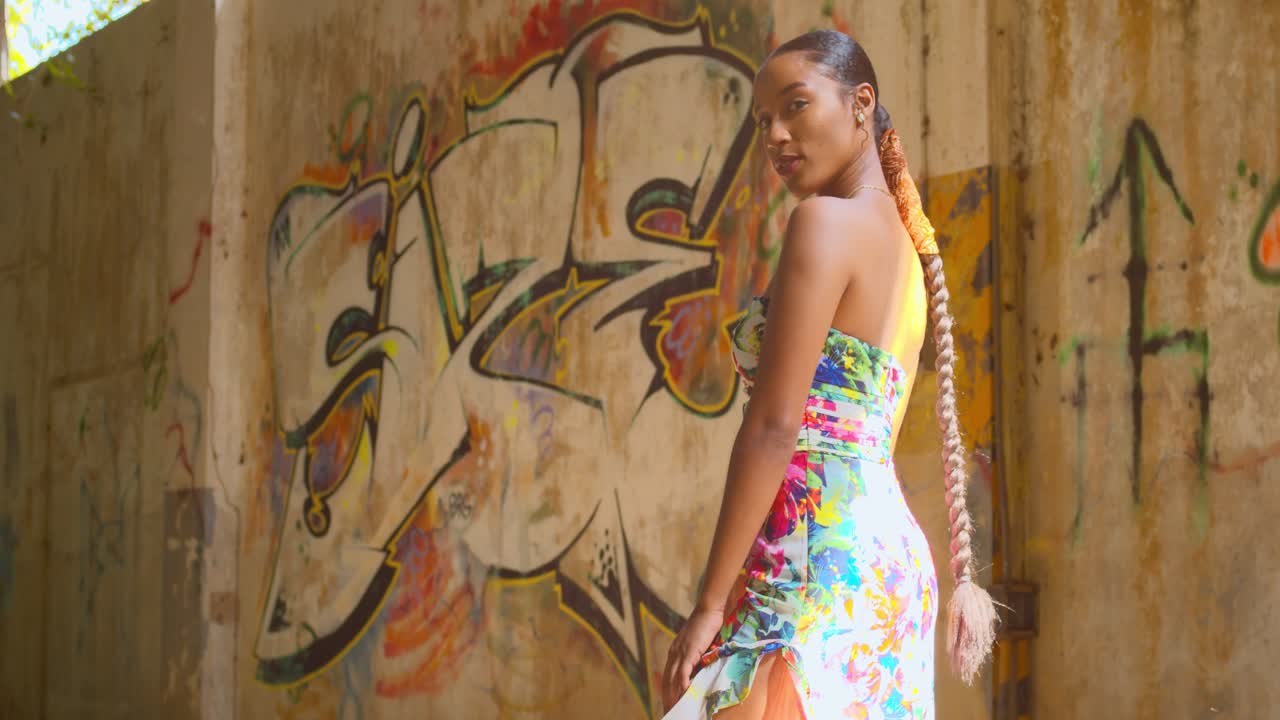 increíble modelo de pie en un almacén abandonado con graffiti en las paredes en el fondo