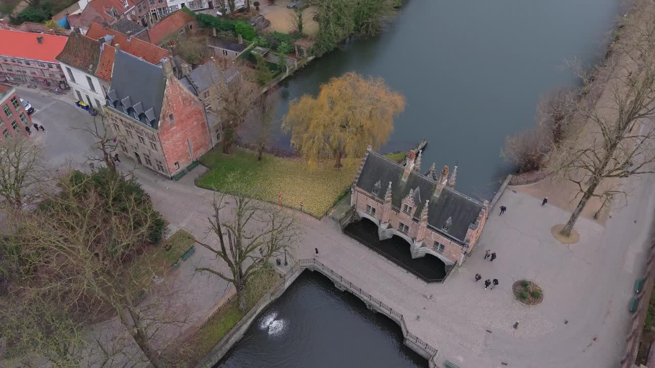 Záběr dronem z vysokého úhlu kroužící kolem zdymadlového domku Sashuis u Jezera lásky. Krásná středověká architektura a vodní kanály Brugg, Belgie, za jasného dne.