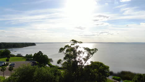 flying over lakeside park on lake apopka, florida as the sun begins to set through the trees