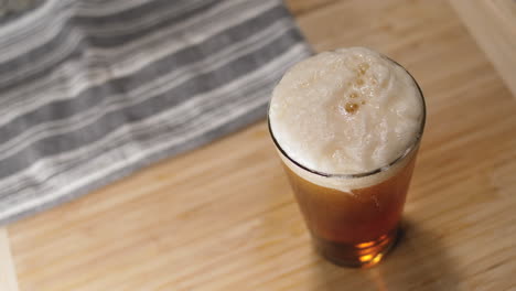 Beer-pouring-into-a-pint-glass-and-bubbles-rising-in-it-on-a-cutting-board