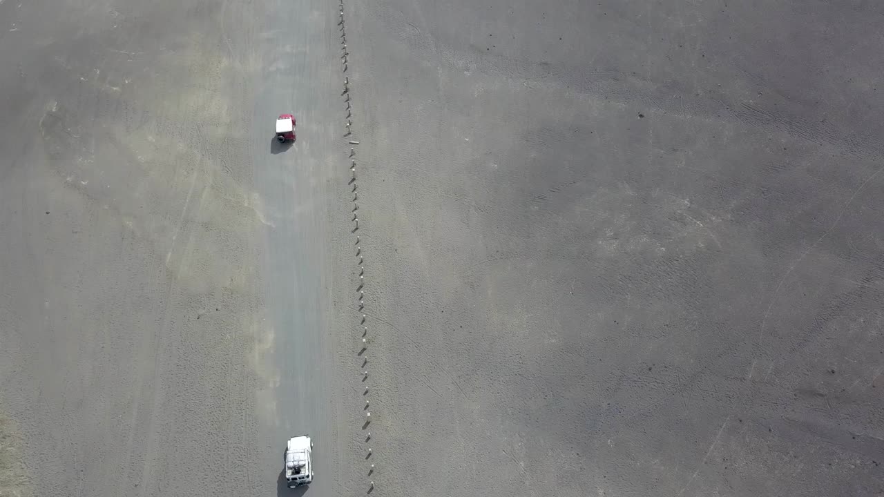 인도네시아 자바의 불모의 회색 브로모 화산 풍경을 통해 활공하는 고속 순항 관광 오프로더 - 공중 비행 추적 샷