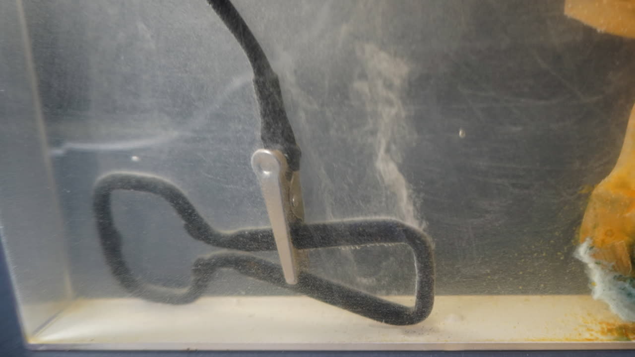 Metal bottle opener in electrolytic bath cleans rust in time-lapse motion