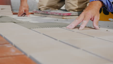 worker hands laid tile on the floor on an open veranda