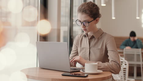 mujer trabajando en una computadora portátil en un café