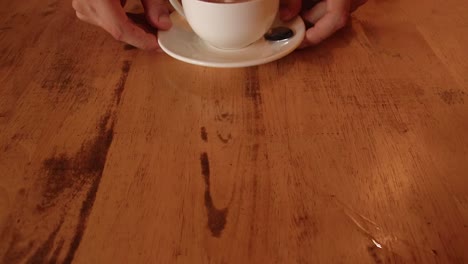 mano empujando hacia adelante una taza de capuchino recién hecha