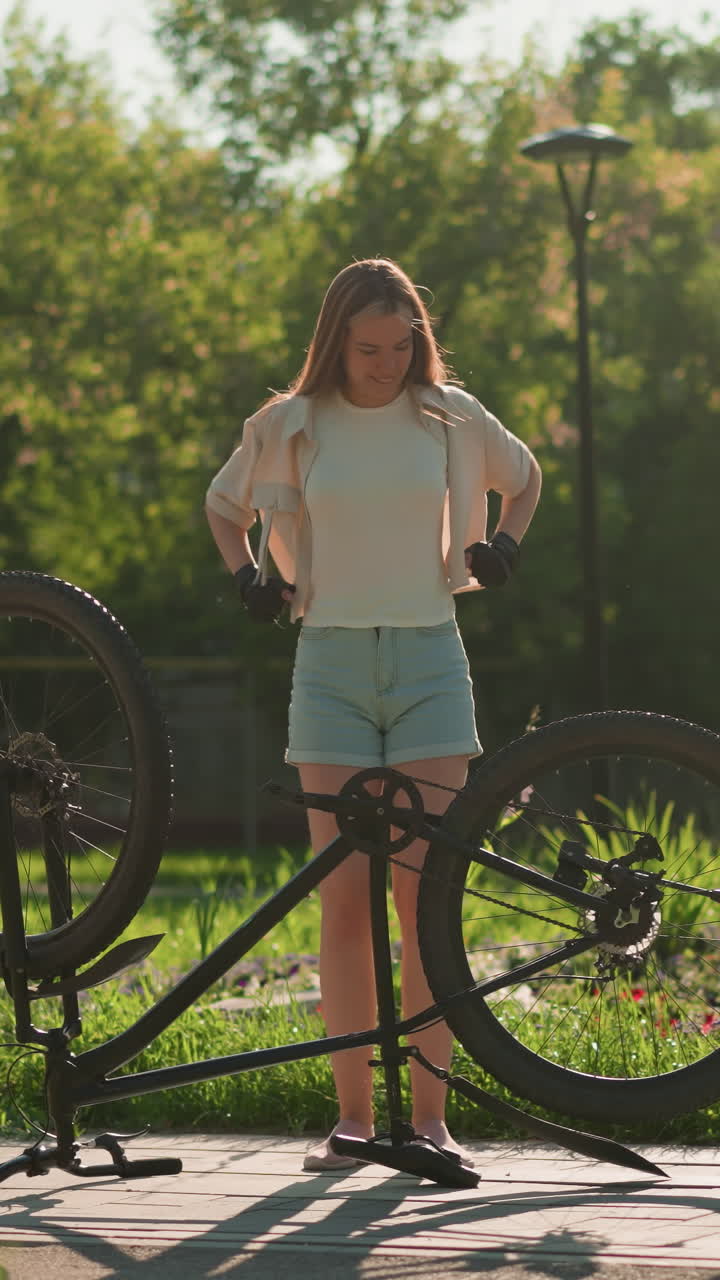 젊은 여자가 거꾸로 된 자전거 에 기게 서서 손을 들어 춤을 추고 환호하며 자전거를 바라보면서 행복과 흥분을 표현하고 있습니다.