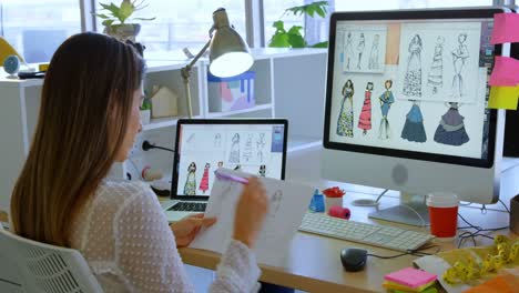 Rear-view-of-Caucasian-female-fashion-designer-working-on-computer-at-desk-in-office-4k