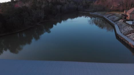 drone footage flying backwards over boat docks with nice houses to the right and calm water at sunset