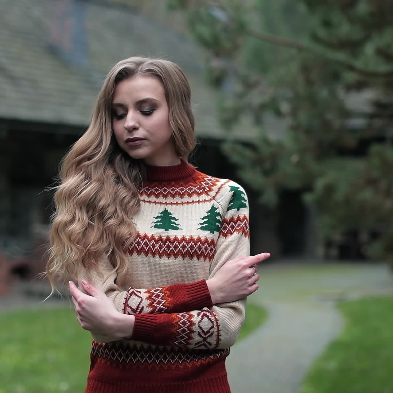 Beautiful blonde woman wearing warm sweater standing at the village house. Long-haired lady in the countryside background