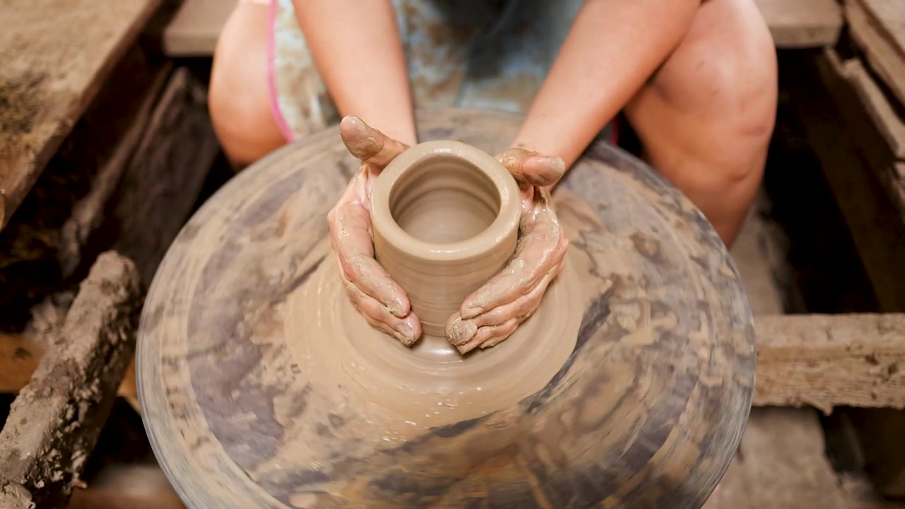Vista ravvicinata dall'alto di un vasaio che modella un recipiente di ceramica in un laboratorio tradizionale