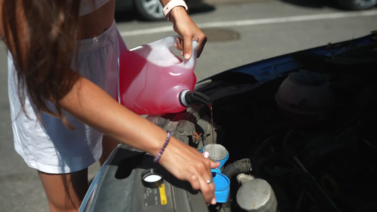 자동차 앞 유리 세척기 액체를 채우는 여성